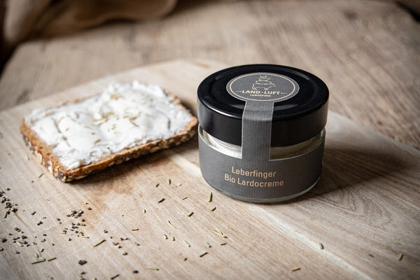 Leberfinger Bio Lardocreme im Glas und link davon als Aufstrich auf einem Vollkornbrot.