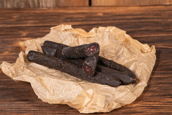 Das Bild zeigt vier Rinderstangerl, von denen eines aufgeschnitten ist. Die hochwertige Wurstspezialität überzeugt mit intensivem Rindfleischgeschmack und eignet sich perfekt als Snack, für Brotzeiten oder Wurstplatten.