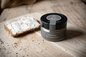 Leberfinger Bio Lardocreme im Glas und link davon als Aufstrich auf einem Vollkornbrot. 